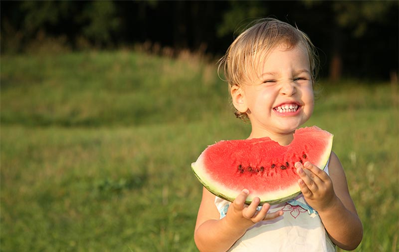 child eating fruit and smiling